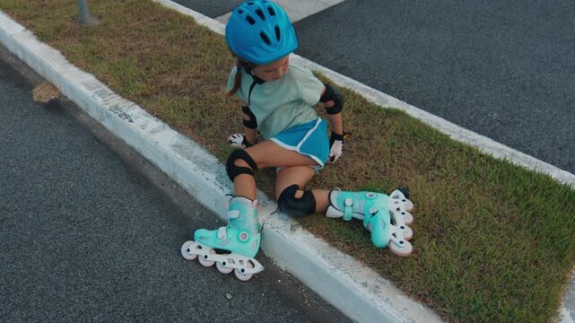 Girl recovers after the fall during roller skating. Girl learns roller skating in the urban safe area and recovers from falling incident