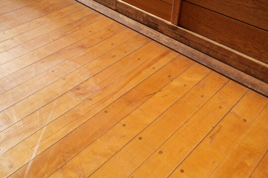 A wooden floor with a clear plastic sheet on it. The floor is brown and has a pattern