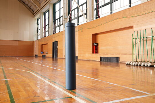 A gymnasium with a black pole in the middle of the floor. The pole is surrounded by a green line