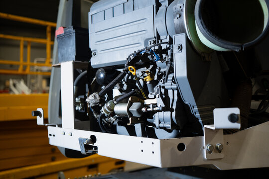 Industrial machinery drivetrain or generator assembly with wiring harness, fluid lines and metal brackets, photographed indoors during service inspection in manufacturing facility