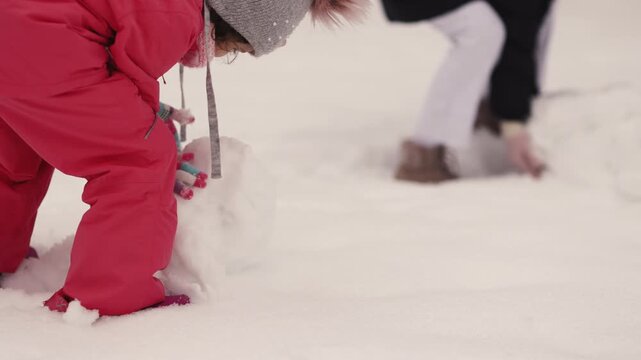Kids make snowballs and play in winter snow at a park in the snowy season