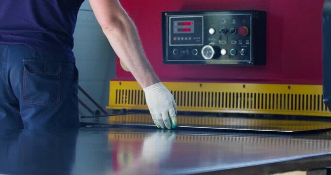 Blue-collar worker cutting task on industrial guillotine machine inside factory. Blue-collar profession and hands-on industrial manufacturing process