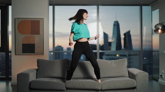 Video of happy young woman dancing and jumping on sofa having good time and celebrating happy days lifestyle.Slow motion.AI Generative.