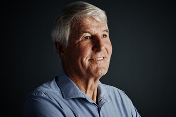 Obraz premium Happy, old man and thinking in studio with retirement idea, contemplation and perspective for decision. Thoughtful, senior person and smile with reflection, memory and nostalgia on dark background.