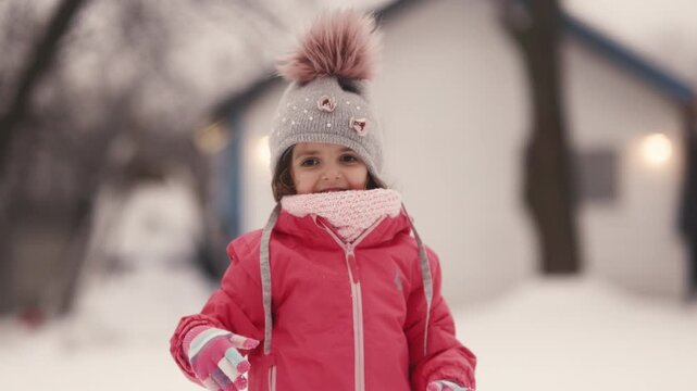 Child plays in snow and throws snowball in backyard during winter day
