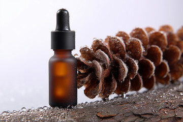 Essential oil amber glass bottle with dropper near pine cone