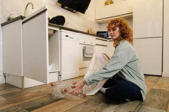 Woman collecting plastic bottles for recycling at home