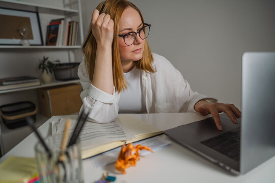 Professional in white shirt working on laptop at corporate office desk