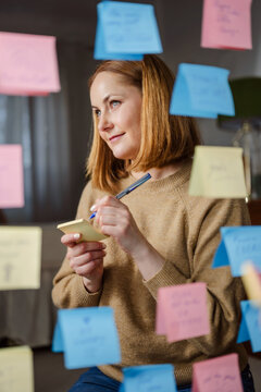 Woman writing positive affirmations on sticky notes for well being