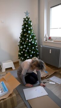 Blonde young woman wrapping Christmas gifts. Vertical view