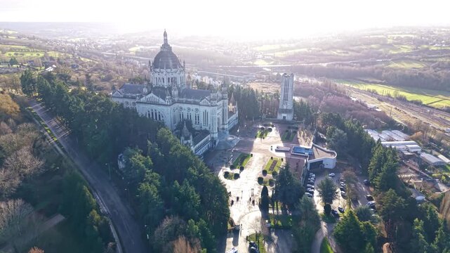 Drone pulling out from Basilique Sainte-Th&eacute;r&egrave;se de Lisieux in Lisieux, Calvados, Normandy, France, revealing the Esplanade Sainte-Th&eacute;r&egrave;se, Jardin du Carmel park and surrounding city and countryside