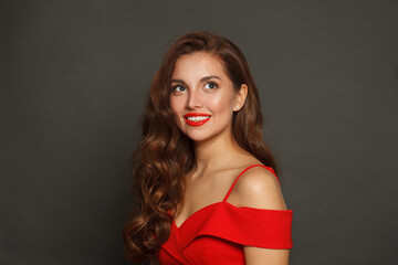 Cheerful fashion model woman with shiny skin, wavy hairstyle and red lips makeup on black background