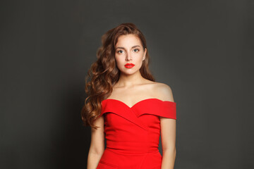 Fototapeta premium Standing fashion model woman with shiny skin, wavy hairstyle and red lips makeup on black background