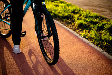 Close up of bicycle wheel on red asphalt bike path in city light. High quality urban infrastructure for safe and comfortable riding.