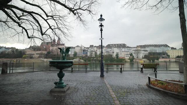 Cinematic pan of the historic dragon fountain and promenade with a view of Basel Minster in Switzerland.