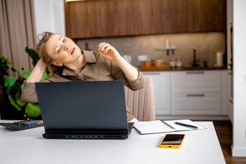 Tired freelancer woman sitting at desk with laptop looking up with exhaustion. Working from home burnout, family budget planning stress, economic pressure, home office fatigue.