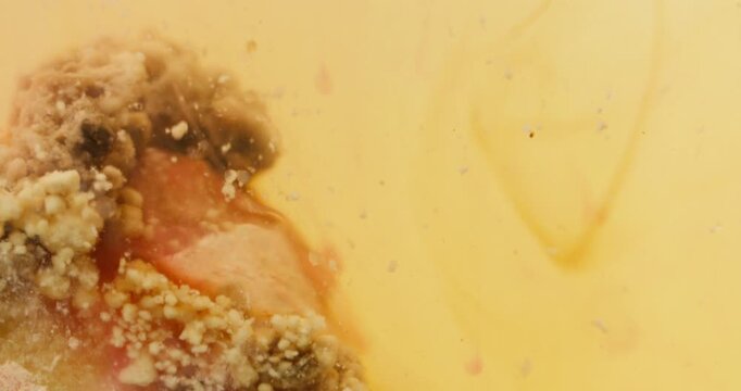 Macro view of orange bath bomb dissolving in water with fizzing bubbles and organic fluid motion