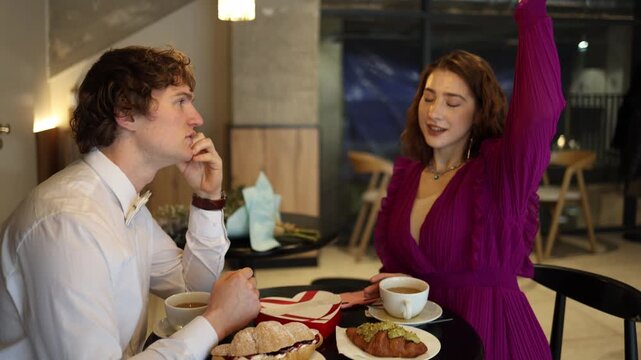 Confident woman passionately talks about herself during cafe date raising hand and dominating conversation while man listens quietly showing imbalance and ego driven communication