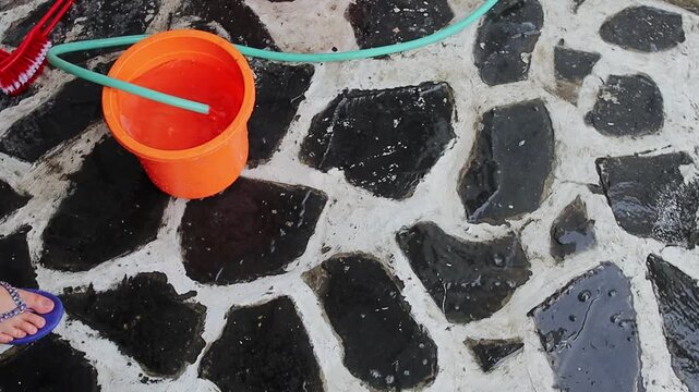 Hands taking water in bucket to water the terrace with dipper