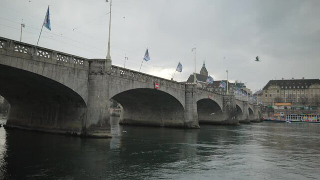 Cinematic pan of the historical Mittlere Bruecke stone bridge over the Rhine river in Basel, Switzerland.