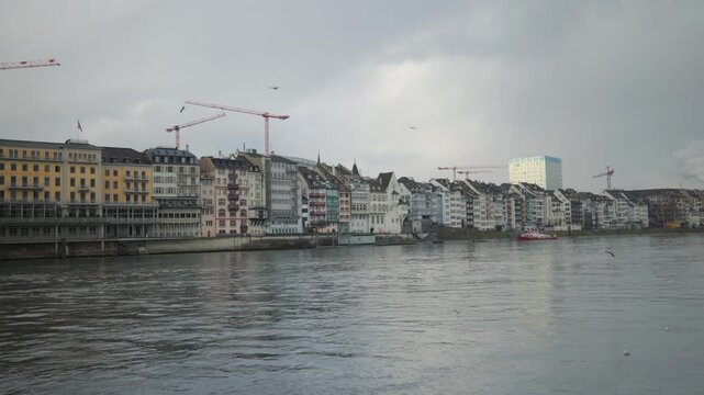 Cinematic view of seagulls flying over the Rhine river with the colorful Kleinbasel skyline in Basel, Switzerland.