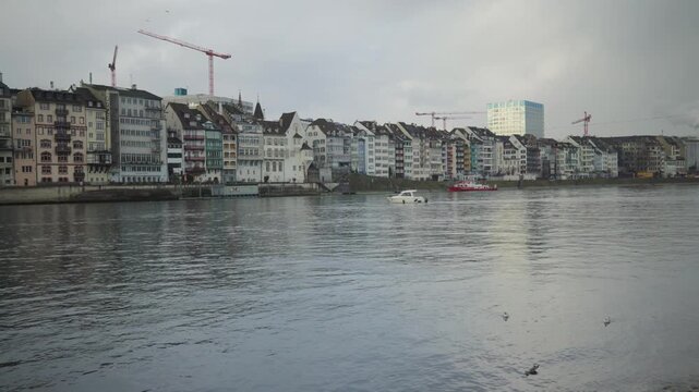 Wide panoramic view of the Rhine river and colorful waterfront houses in Basel, Switzerland.
