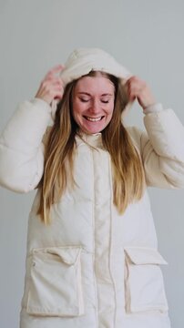 Vertical video of a girl in a white down jacket putting on a hood