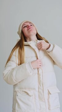 Vertical video of a girl zipping up a white jacket
