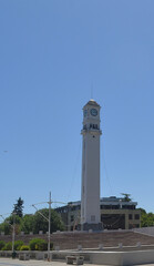 Modern White Clock Tower Standing Tall in Public City Park Under Clear Blue Sky