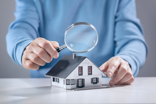 House model with man holding magnifying glass home inspection or searching for a house
