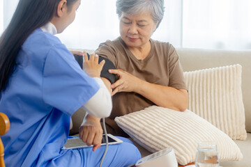 Obraz premium Home Care Nurse Measuring Blood Pressure of Senior Woman During Home Health Check. Elderly care, wellness monitoring, and supportive healthcare at home. Caregiver Checking Blood Pressure for Elderly.