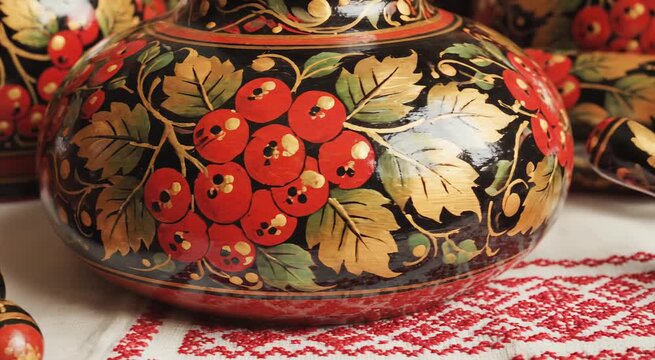 Traditional folk art painted wooden kitchenware with cranberry and leaf patterns on embroidered textile for cultural gift