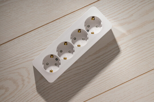 Unpackaged white power strip with four sockets placed on a wooden surface.