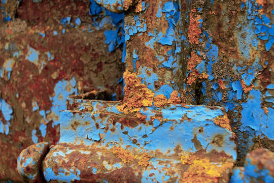 Close-up of a corroded metal surface with blue paint flakes.