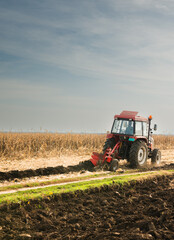 Obraz premium Tractor plowing field the land at sunset