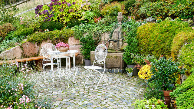 Terrasse mit Tisch, Stuhl und Brunnen sowie diversen Pflanzen	