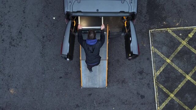 Roadie loading flight case into van aerial view