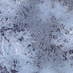 Ice Crystals and Frost Patterns on Glass, Winter Abstract Background. Detailed macro view of ice crystals and frost patterns forming on glass in freezing temperatures. 