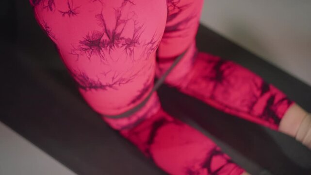 female athlete in pink leggings kneeling on black mat performing slow glute activation, closeup of patterned leggings, soft studio light, controlled breathing, lowimpact warmup for hip mobility