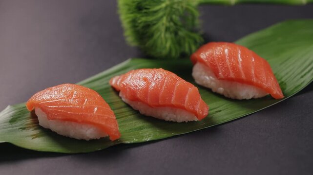 closeup of fresh salmon nigiri sushi on a green leaf.