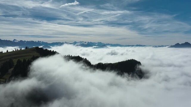Aerial view of green mountain ridge above sea of clods with wispy sky