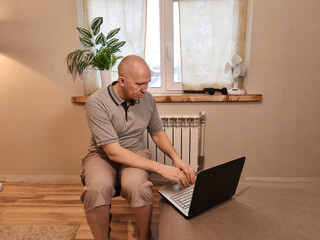Adult man freelancer working remotely on laptop at cozy home office. Telecommuting lifestyle and digital nomad concept for online business.