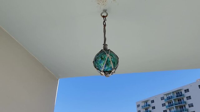 Decorative crystal ball hanging from ceiling and swaying in wind