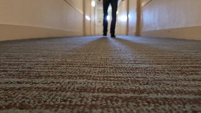 Man passing floor level camera and walking along corridor