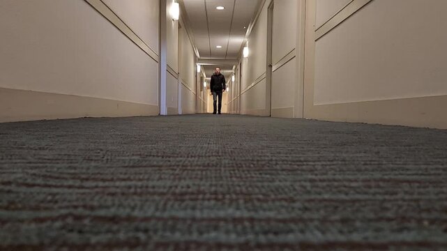 Man slowly approaching floor level camera in corridor