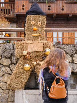 in the traditional Sauris mountain Carnival, A woman looks at a straw figure with a black hood, wooden eyes, an orange nose, and a corn cob mouth. Sauris,Friuli Venezia Giulia,Italy