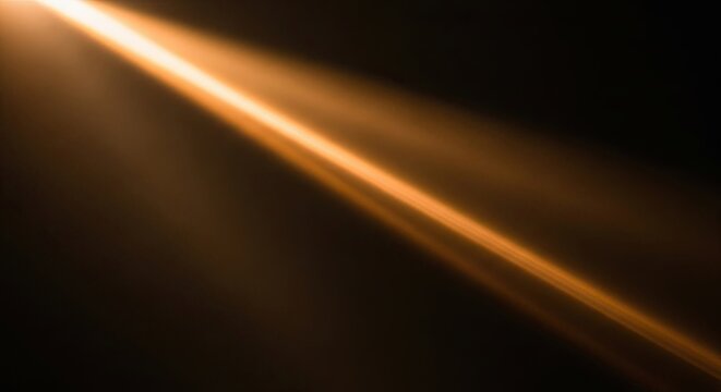 Abstract golden light beam on dark background with lens flare effect.
