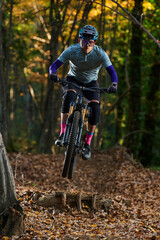 Intense Mountain Biker Jumping Over Log on Forest Trail During Autumn Ride