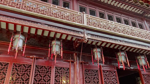 Traditional Chinese style balcony with beautiful roofs of a building in a blur foreground of old roof tiles and hanging chain of red lanterns in the front	