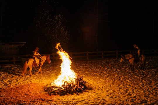 During the carnival procession, two people on horseback circle a large bonfire at night. Sauris,Friuli Venezia Giulia,Italy